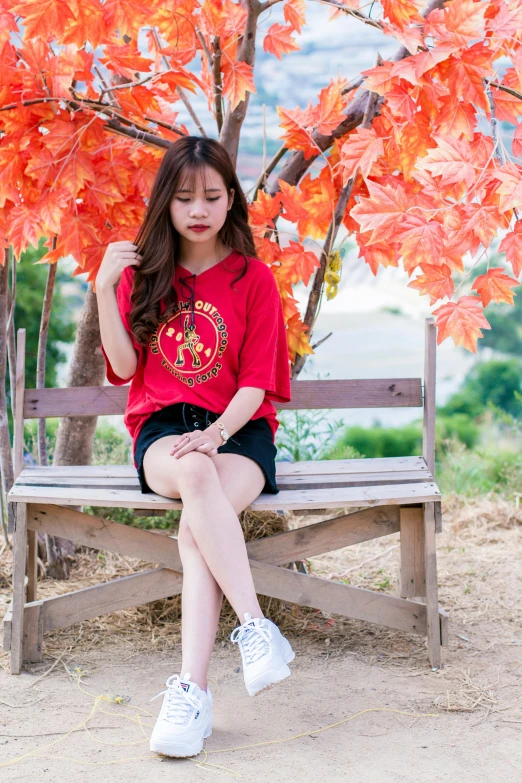 a woman sitting on a bench in front of a tree, red shirt, ulzzang, in tshirt, premium