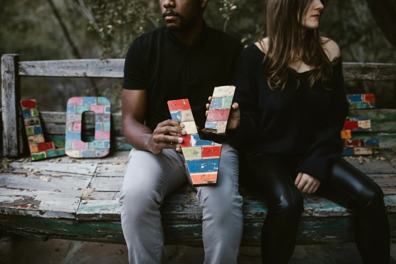 a man and a woman sitting on a bench, an album cover, trending on unsplash, hand painted textures on model, cardistry, color blocks, vannessa ives
