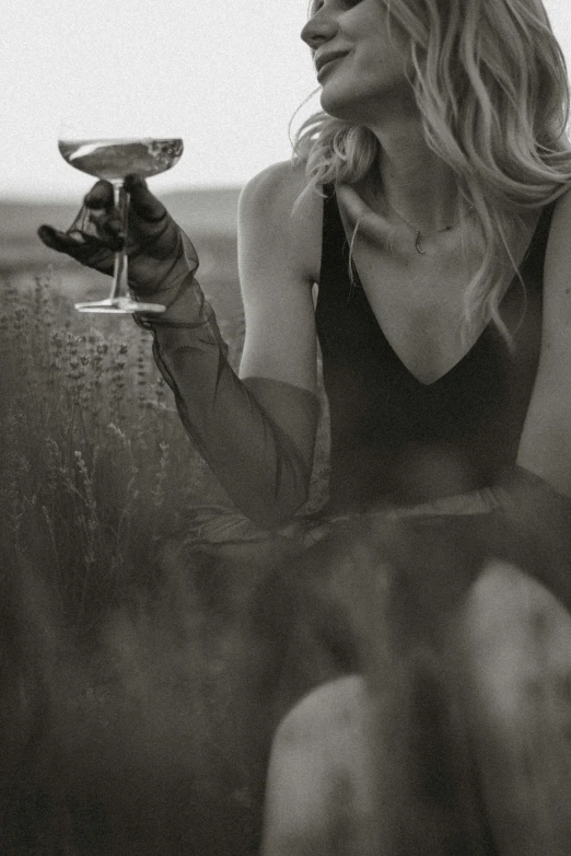 a woman sitting in a field holding a wine glass, a black and white photo, inspired by Peter Lindbergh, unsplash, renaissance, black gloves, close up of a blonde woman, gentlemens dinner, decolletage