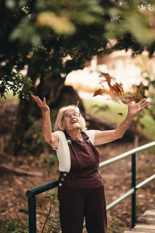 an older woman throwing leaves in the air, pexels contest winner, square, looking off to the side, wholesome, very old