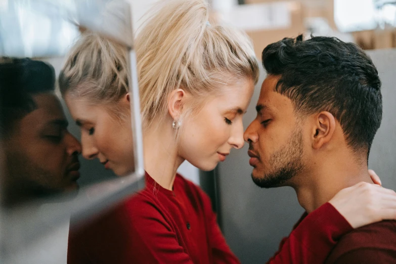 a man and a woman standing next to each other, trending on pexels, romanticism, light stubble with red shirt, making out, mix of ethnicities and genders, looking in mirror