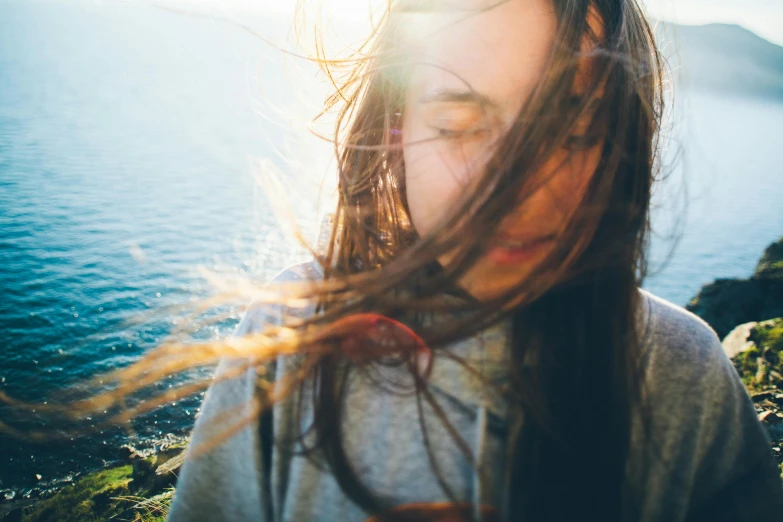 a woman with her hair blowing in the wind, by Niko Henrichon, trending on unsplash, overexposed sunlight, glare on the water, selfie of a young woman, hestiasula head