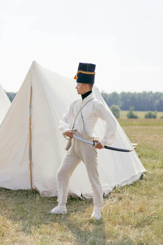 a man standing in front of a tent with a sword, a colorized photo, inspired by Illarion Pryanishnikov, unsplash, white uniform, battle of waterloo, joel meyerowitz, on the field