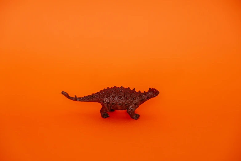 a toy dinosaur on an orange background, by Adam Marczyński, trending on unsplash, magic realism, ffffound, chocolate, single color, on simple background