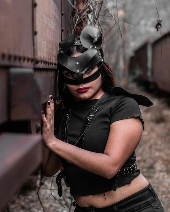 a woman wearing a mask standing next to a train, inspired by Hedi Xandt, pexels contest winner, kylie jenner as catwoman, provocative indian, postapocalyptic style, slightly minimal
