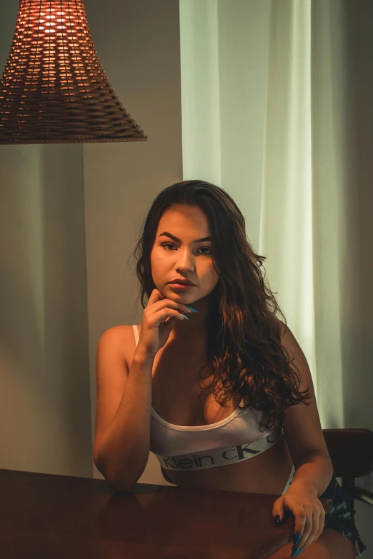 a woman sitting at a table in front of a lamp, inspired by Elsa Bleda, unsplash, wearing a low cut tanktop, south east asian with round face, 🤤 girl portrait, 5 0 0 px models