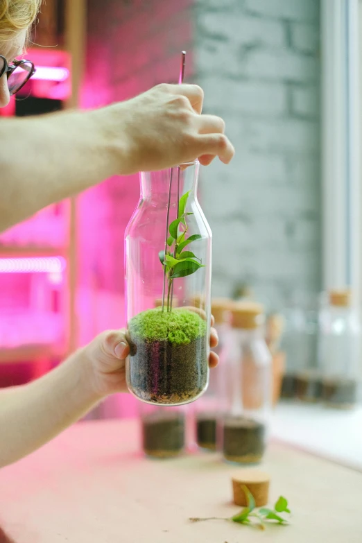 a close up of a person holding a plant in a bottle, a picture, futuristic product design, indoor lab scene, vibrant colour, easy to use