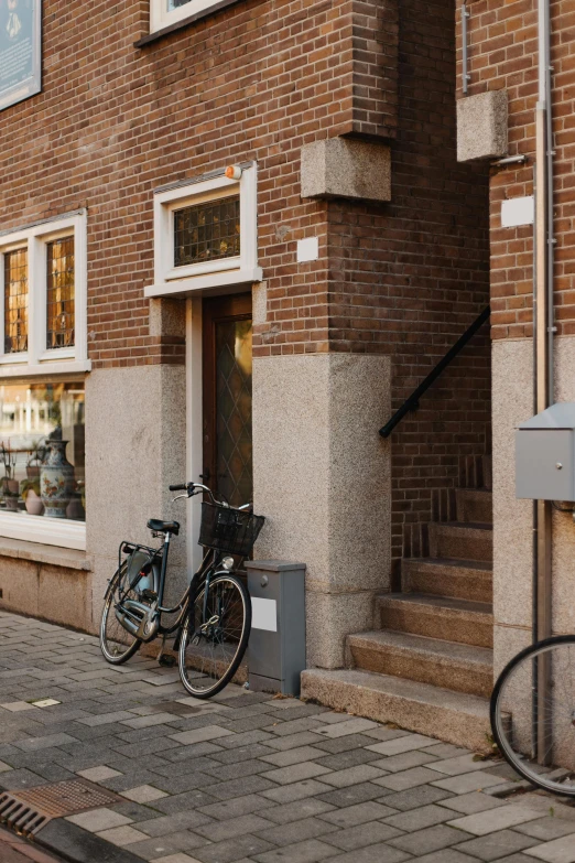 a couple of bikes parked in front of a building, by Jan Tengnagel, small path up to door, exiting store, brown, exterior photo