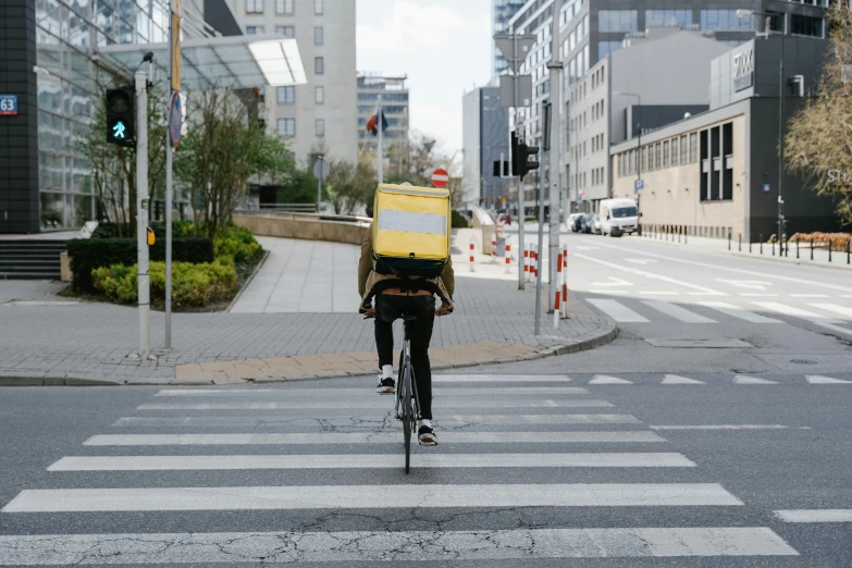 a person riding a bike on a city street, carrying a tray, head down, square, may 1 0