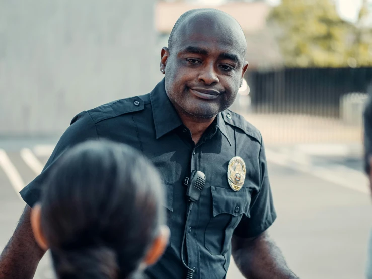 a police officer talking to a group of people, a portrait, by Winona Nelson, pexels contest winner, smiling at camera, panel of black, schools, nearest neighbor