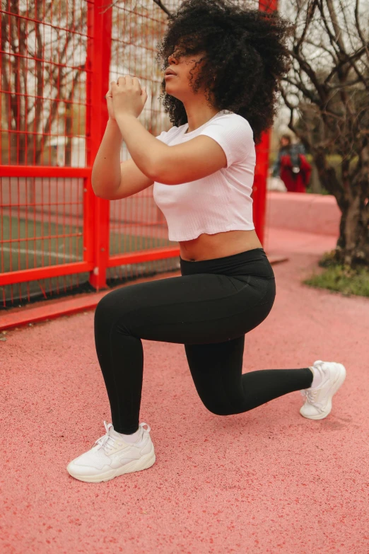 a woman in a white shirt and black leggings is squatting, pexels contest winner, at a park, lunging at camera :4, shaped derriere, schools