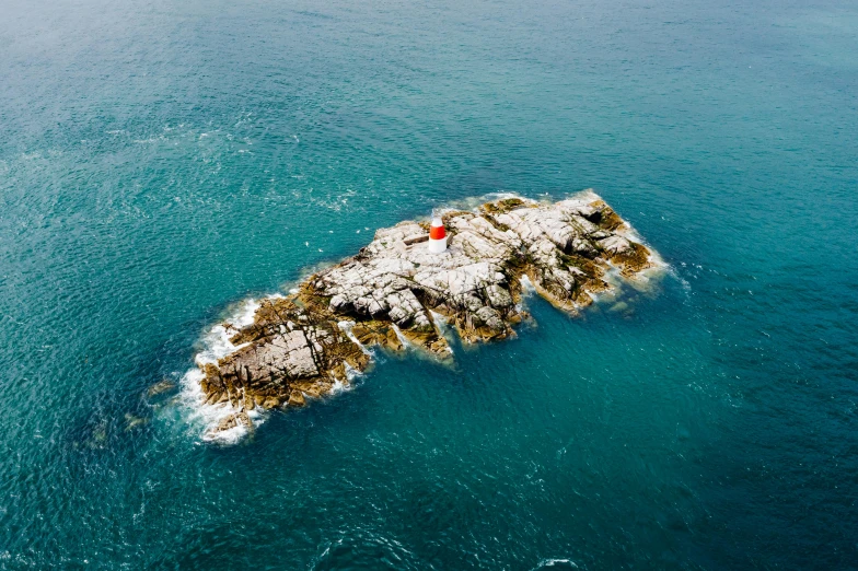 a small island in the middle of the ocean, by Adam Marczyński, pexels contest winner, land art, perched on a rock, northern france, hashima island, bird\'s eye view