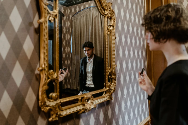 a man that is standing in front of a mirror, by Emma Andijewska, pexels contest winner, timothee chalamet, hotel room, gold, behind the scenes photo