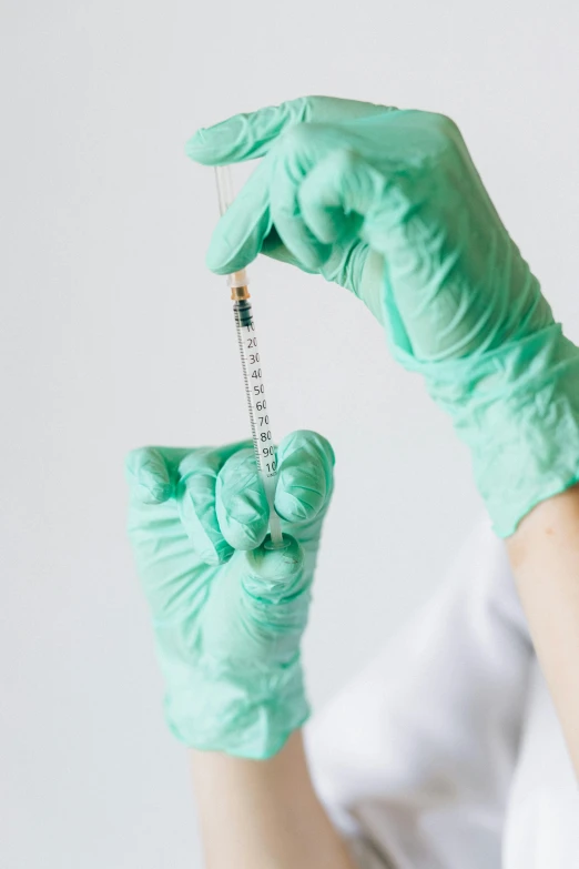 a person in a white shirt and green gloves holding a syssor, plasticien, holding a syringe, trending photo, implants, multiple stories