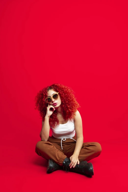 a woman with red hair sitting on the floor, trending on pexels, solid color backdrop, red sunglasses, ashteroth, metallic red