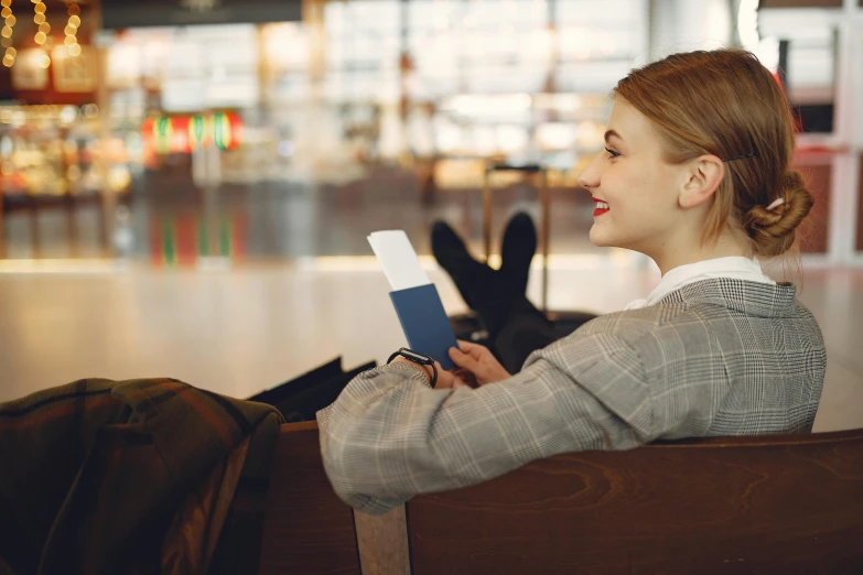 a woman sitting on a bench reading a book, happening, airport, warm friendly face, profile image, thumbnail