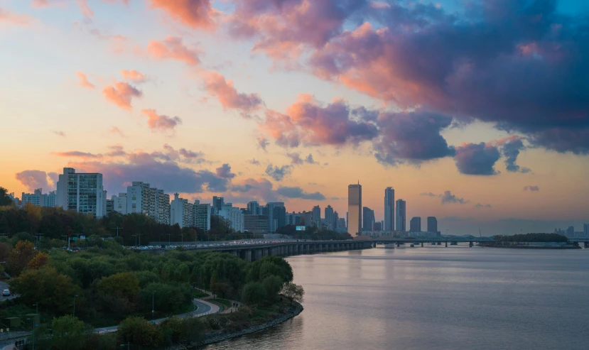 a large body of water with a city in the background, by Jang Seung-eop, pexels contest winner, pink clouds in the sky, great river, autumn season, youtube thumbnail