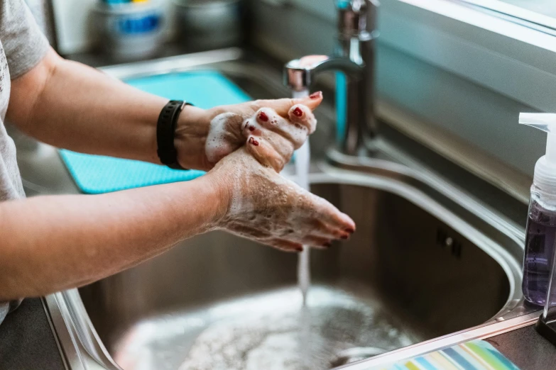 a woman washing her hands in a kitchen sink, by Julia Pishtar, pexels, fan favorite, carved soap, tyler west, furry arms