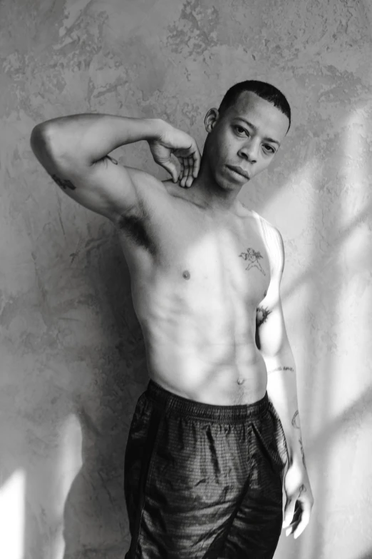 a black and white photo of a man leaning against a wall, physical : tinyest midriff ever, gustavo fring, boxer, circa 1 9 9 9