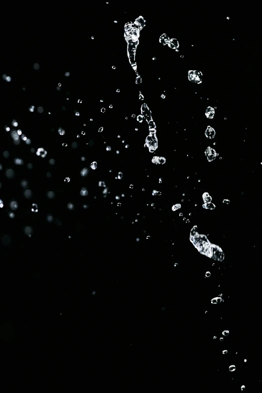 an orange falling into the water on a black background, an album cover, pexels, underwater bubbles background, black, downpour, grainy footage