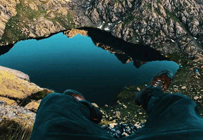 a person standing on top of a mountain next to a lake, pexels contest winner, hyperrealism, detailed shot legs-up, lake blue, sitting in a reflective pool, looking down from above