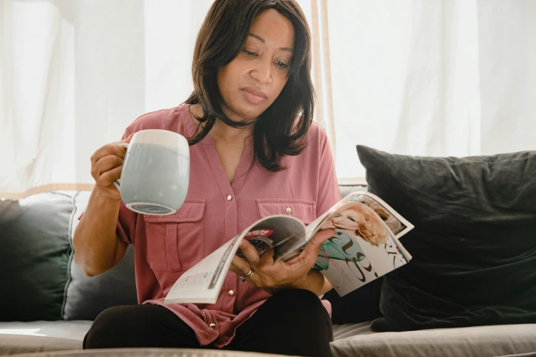 a woman sitting on a couch reading a magazine, by Carey Morris, pexels contest winner, happening, is ((drinking a cup of tea)), joanna gaines, wearing pajamas, walking down