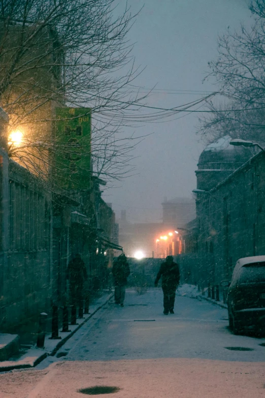 a person walking down a snowy street at night, post - soviet courtyard, moody morning light, distant hooded figures, trending photo