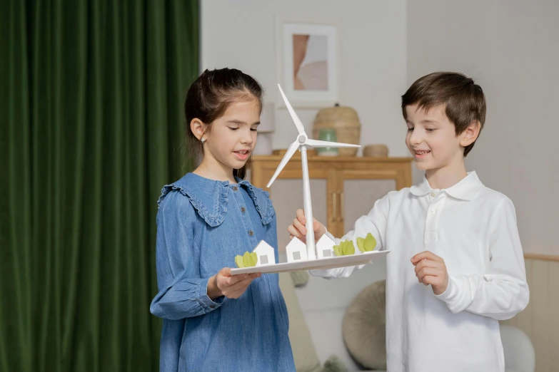 a couple of kids standing next to each other, pexels contest winner, conceptual art, green energy, tabletop model, carrying a tray, windmill