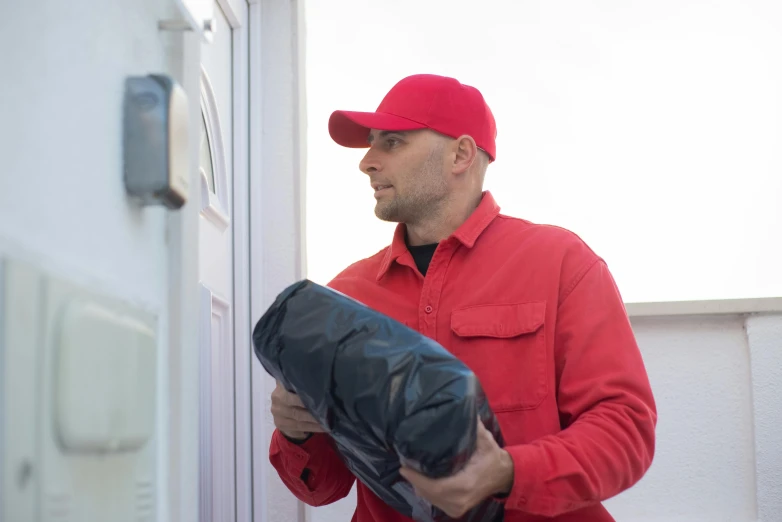 a man in a red shirt holding a black object, delivering mail, profile image, red door blonde, temporary emergency shelter