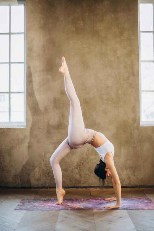 a woman doing a handstand pose on a yoga mat, a picture, by Arabella Rankin, unsplash, arabesque, wearing white leotard, arcs, studio photo, 15081959 21121991 01012000 4k