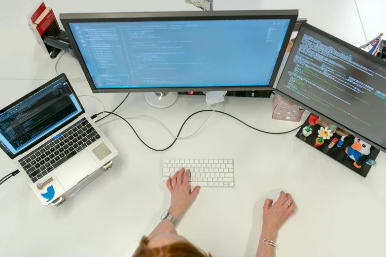 a woman sitting at a desk working on a computer, a computer rendering, by Carey Morris, unsplash, wide high angle view, computer code, photographed for reuters, computer screens