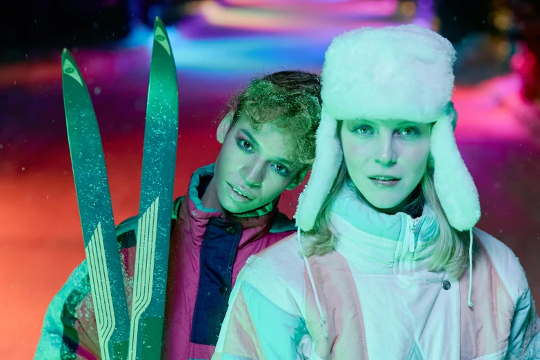 a couple of people standing next to each other holding skis, a portrait, inspired by David LaChapelle, trending on pexels, kitsch movement, luminescent fabrics, lesbians, (snow), promotional image