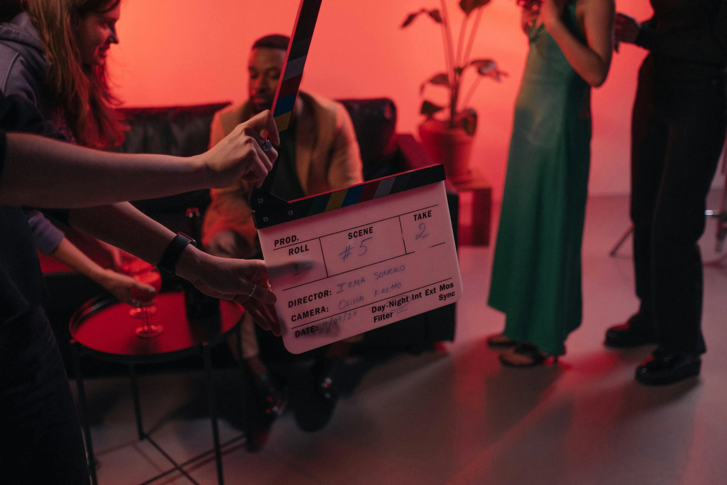 a woman holding a movie clap in front of a group of people, by Romain brook, pexels contest winner, cinematic and dramatic red light, tv commercial, on set, instagram post