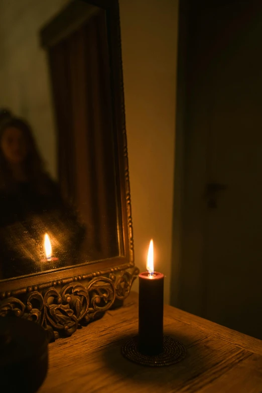 a candle sitting on top of a wooden table next to a mirror, inspired by Elsa Bleda, renaissance, amanda lilleston, gothic lighting, person in foreground, lumen reflections