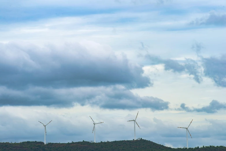 a herd of cattle standing on top of a lush green field, by Carey Morris, pexels contest winner, wind turbines, sky with swirling clouds, minimalistic composition, grey