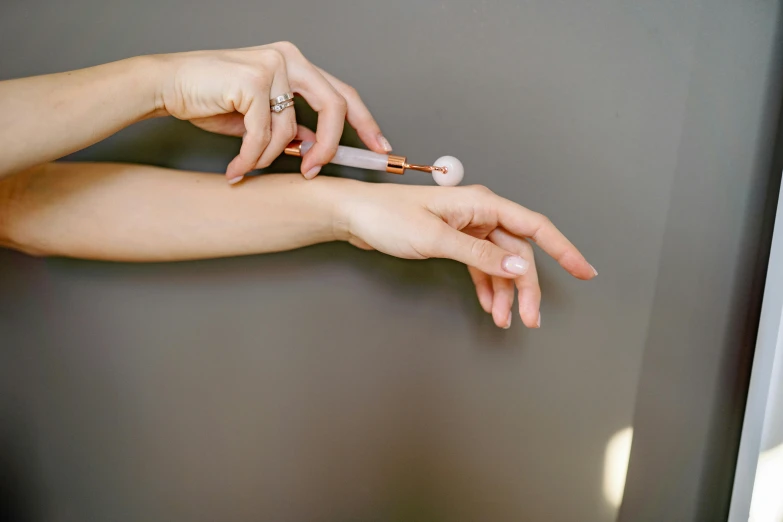 a close up of a person holding a toothbrush, by Emma Andijewska, magic realism, ivory and copper, partially cupping her hands, syringe, a high angle shot