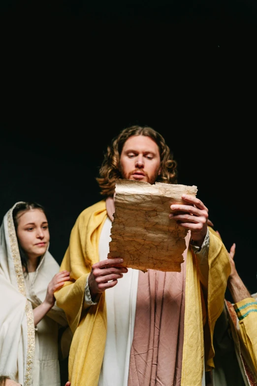 a group of people standing next to each other, an album cover, by Everett Warner, trending on unsplash, renaissance, religious robes, he is holding a large book, ( ( theatrical ) ), jesus