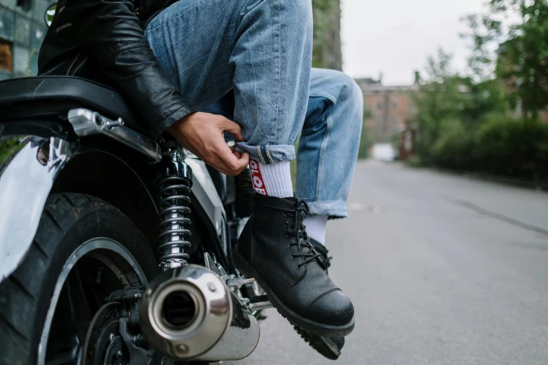 a man sitting on the back of a motorcycle, trending on pexels, jeans and black boots, wearing kneesocks, profile image, multiple stories