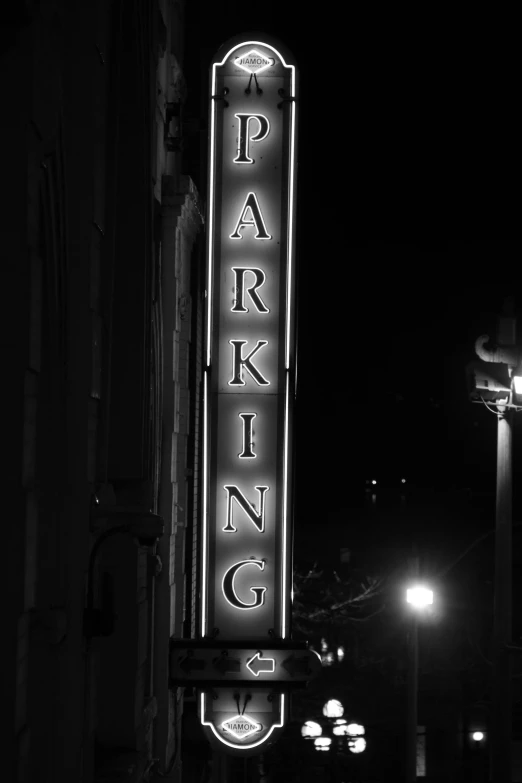 a black and white photo of a parking sign, by Dave Melvin, happening, night life buildings, theater, car lights, dark. no text