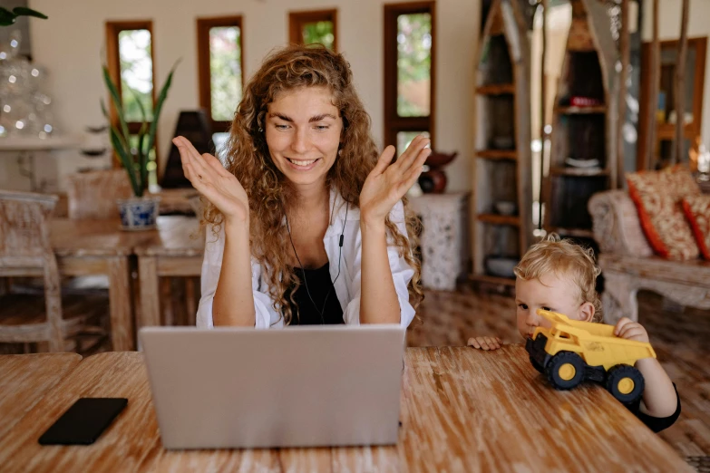 a woman sitting at a table with a child in front of a laptop, pexels contest winner, waving, avatar image, bottom angle, maintenance