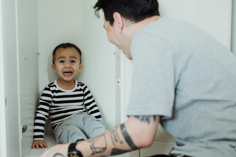 a young boy sitting on top of a toilet next to a man, by Emma Andijewska, pexels contest winner, tattooed, earing a shirt laughing, 2 years old, thumbnail