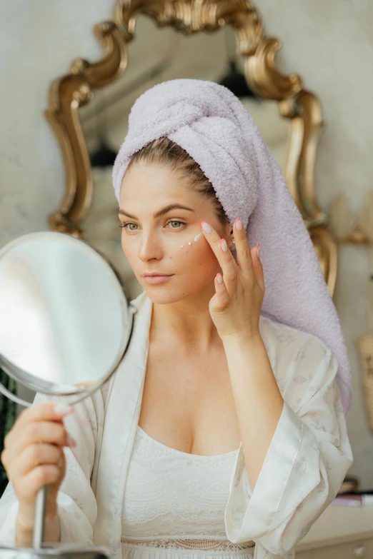 a woman with a towel on her head in front of a mirror, soft round face, wearing a grey robe, blending, cream