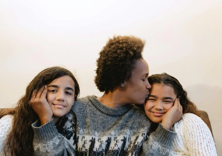 a couple of women sitting next to each other, pexels contest winner, incoherents, with a kid, she has olive brown skin, hugging each other, avatar image