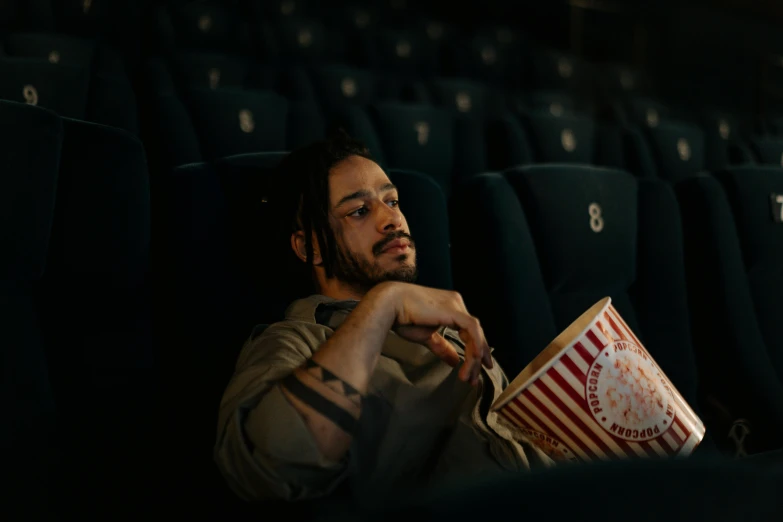 a man sitting in a movie theater with a bucket of popcorn, a portrait, pexels contest winner, jason momoa, alessio albi, [ theatrical ]