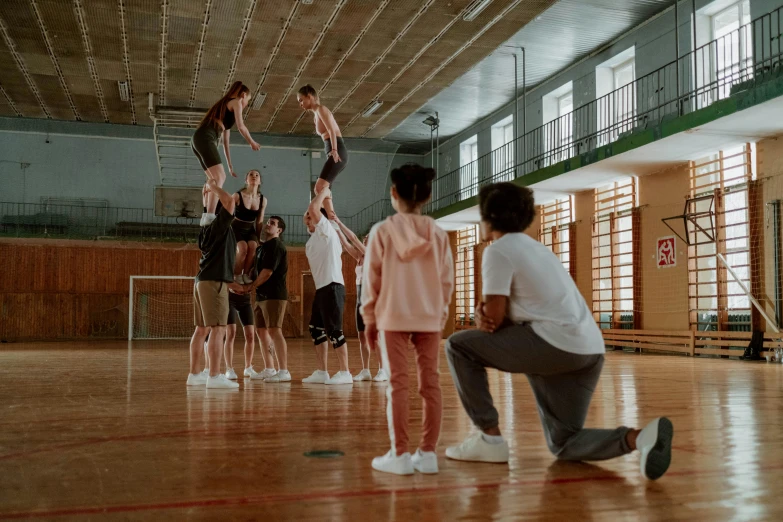 a group of people standing on top of a basketball court, a picture, by Emma Andijewska, pexels contest winner, tall ceilings, school class, standing on two legs, working out