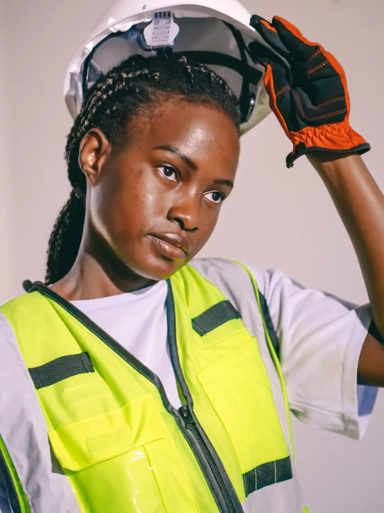 a woman wearing a hard hat and safety vest, inspired by Afewerk Tekle, trending on pexels, black teenage girl, white uniform, promo image, non binary model