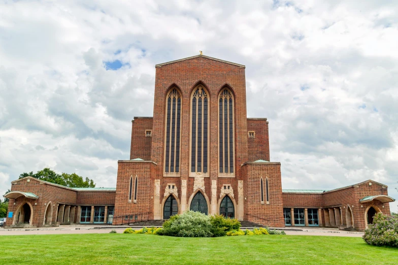 a large brick building sitting on top of a lush green field, inspired by Barthélemy d'Eyck, unsplash, modernism, chrome cathedrals, facing front, bronze, brown