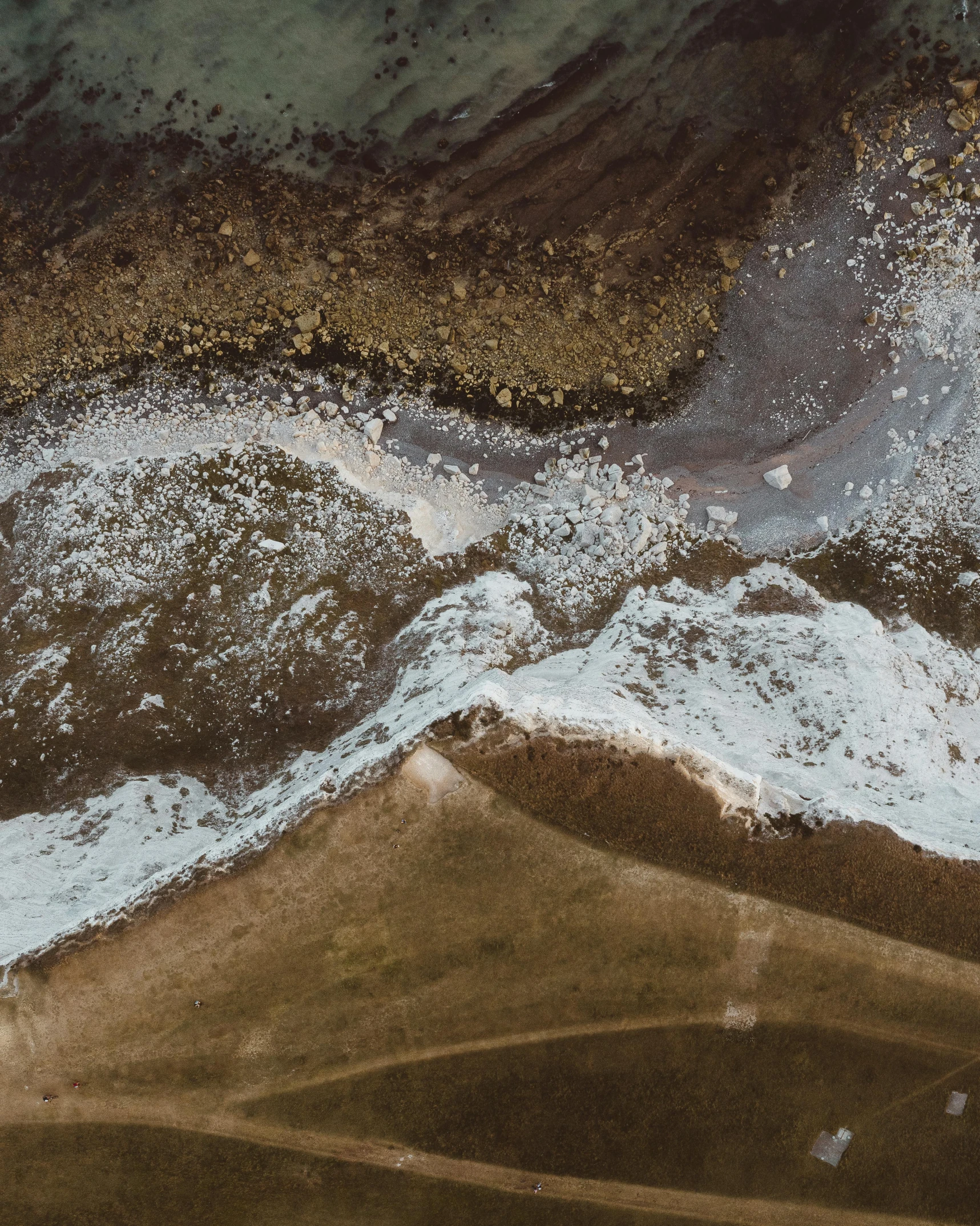 a man riding a surfboard on top of a sandy beach, a microscopic photo, trending on unsplash, analytical art, brown mud, seen from a plane, thumbnail, jelly - like texture. photograph