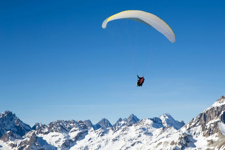 a person that is in the air with a parachute, by Peter Churcher, pexels contest winner, hurufiyya, snow capped mountains, clear blue skies, avatar image, 9 9 designs