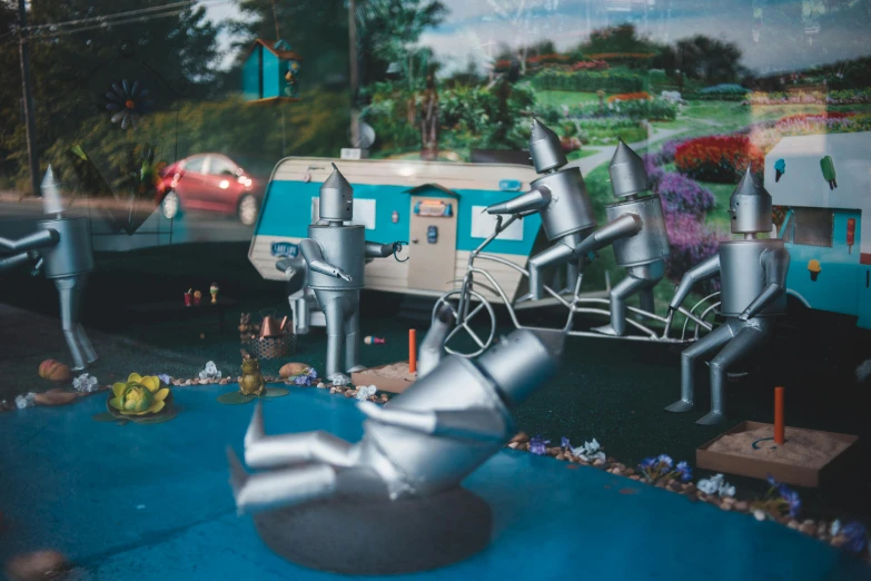 a group of tin man figurines sitting on top of a table, a surrealist sculpture, by Matt Cavotta, pexels contest winner, kinetic art, polaroid photo of trailerpark, retro spaceships parked outside, flowers around, blue slide park